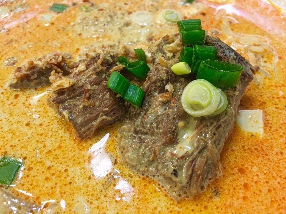 Beef in a red curry broth topped with green onion