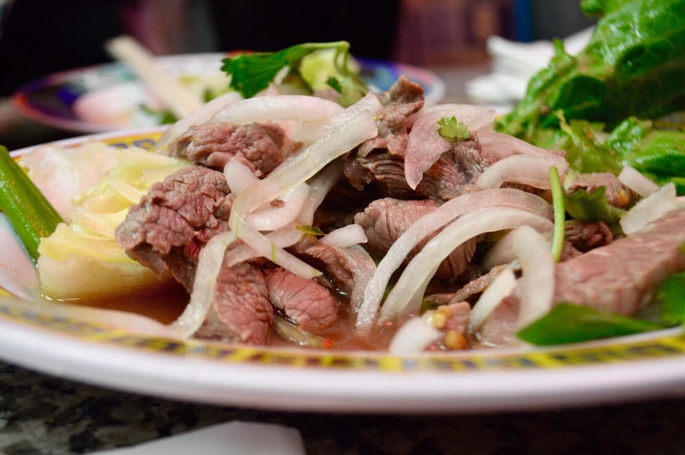 Sliced rare beef with onion and fresh herbs